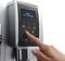 A hand selects a drink on a modern fully automatic coffee machine with a digital display and various selection options.