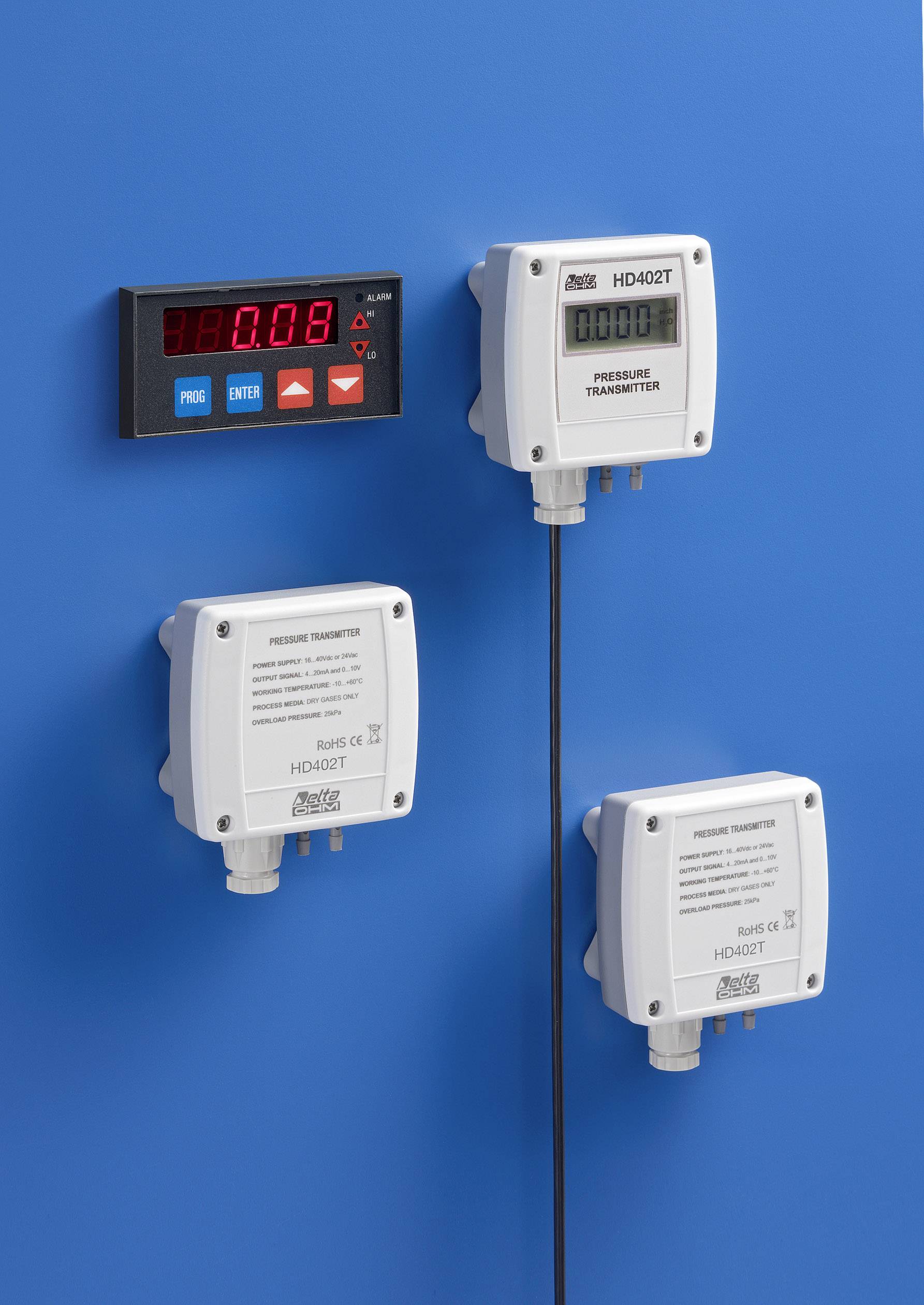 'Three pressure transmitters and a digital display device on a blue wall. The display shows a value of 0.08.'