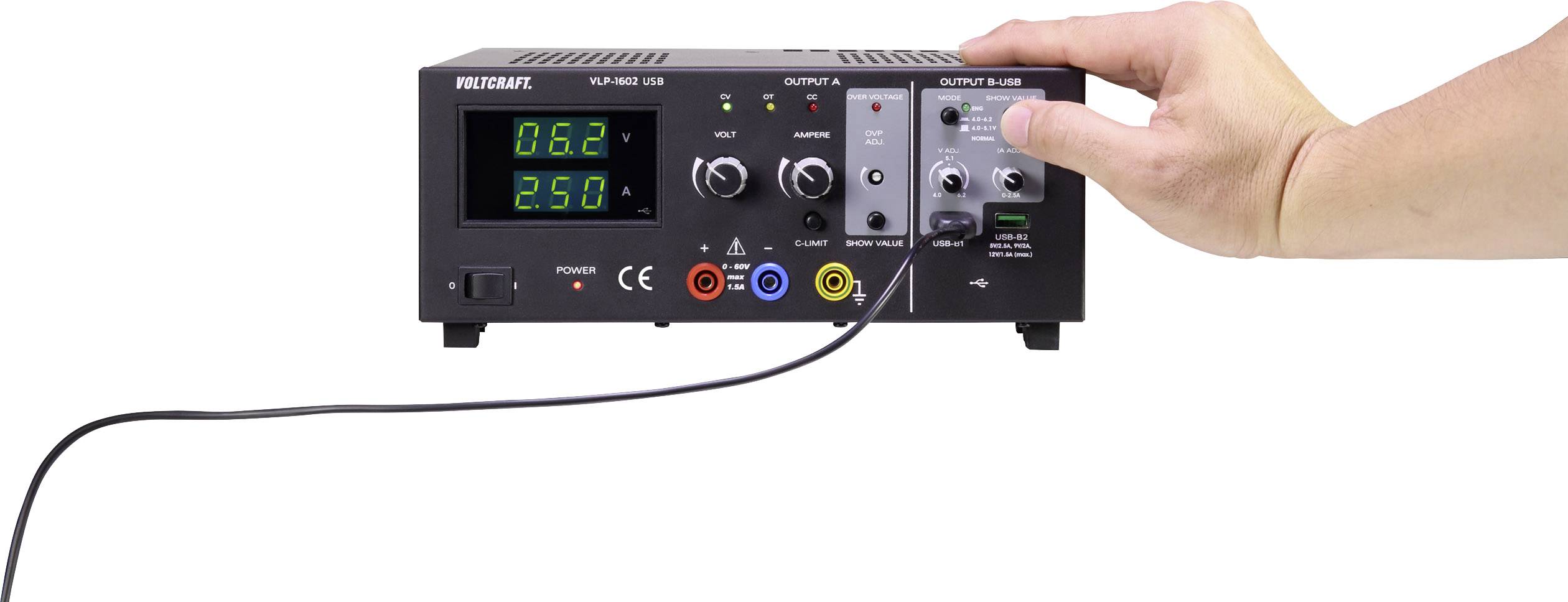 'A hand operates an adjustable power supply with digital displays for voltage and current.'