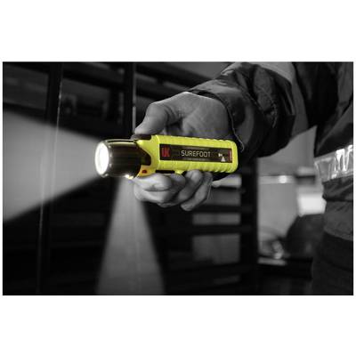 A person is holding a yellow torch, illuminating a dark room. The focus is on the hand and the torch.