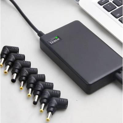 A laptop charger with detachable adapters featuring different connector sizes is lying next to a laptop keyboard.