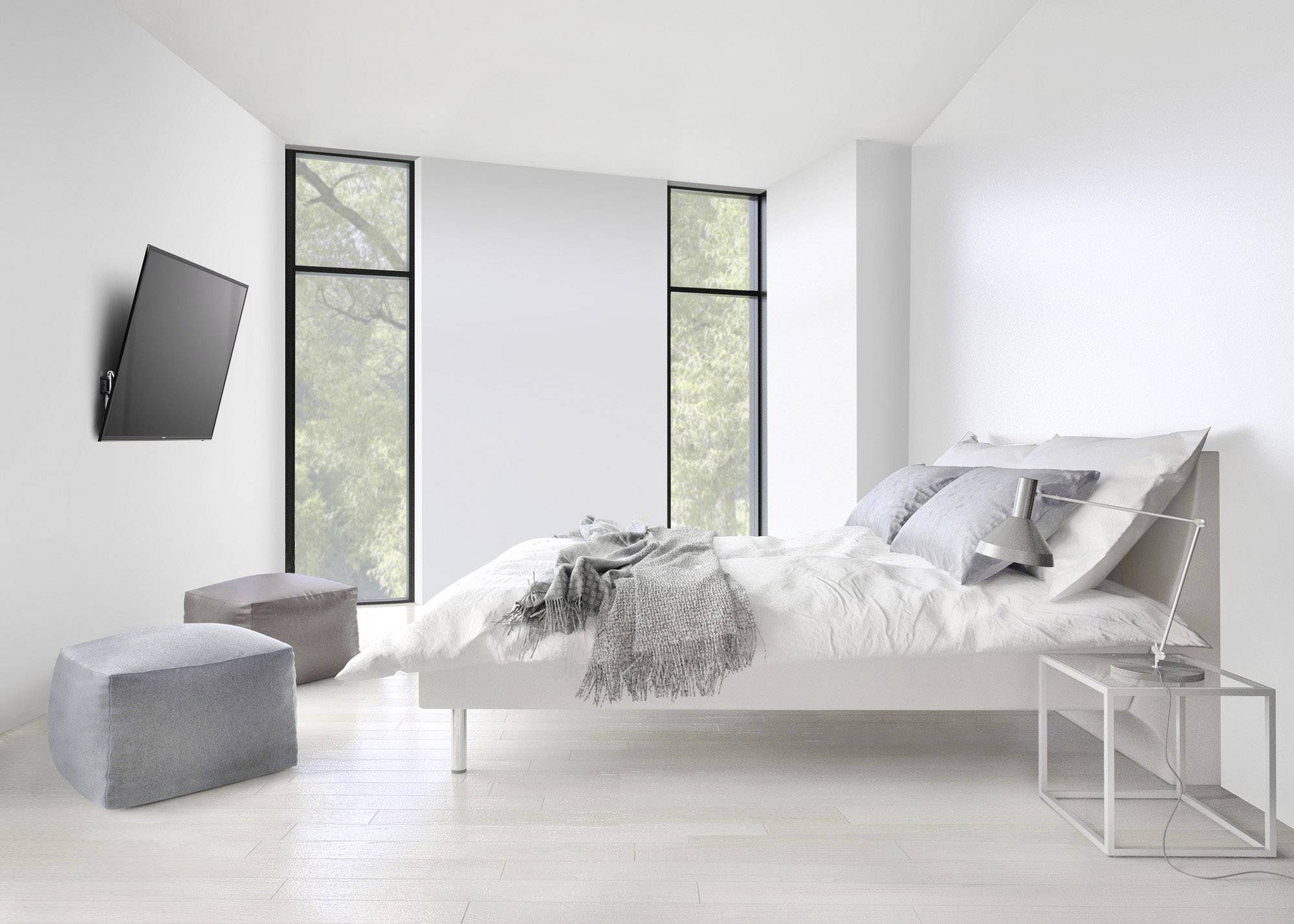 Bright bedroom with a bed, grey cushions and throws, a modern bedside table and a wall-mounted television positioned at an angle.