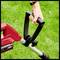 A person is holding the handle of a red and black lawnmower standing on green grass.
