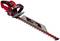 Red electric hedge trimmer with black handle and protective cover, pictured against a white background.
