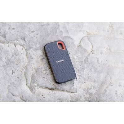 External SSD by SanDisk on a stone surface, compact and portable, ideal for mobile data storage.