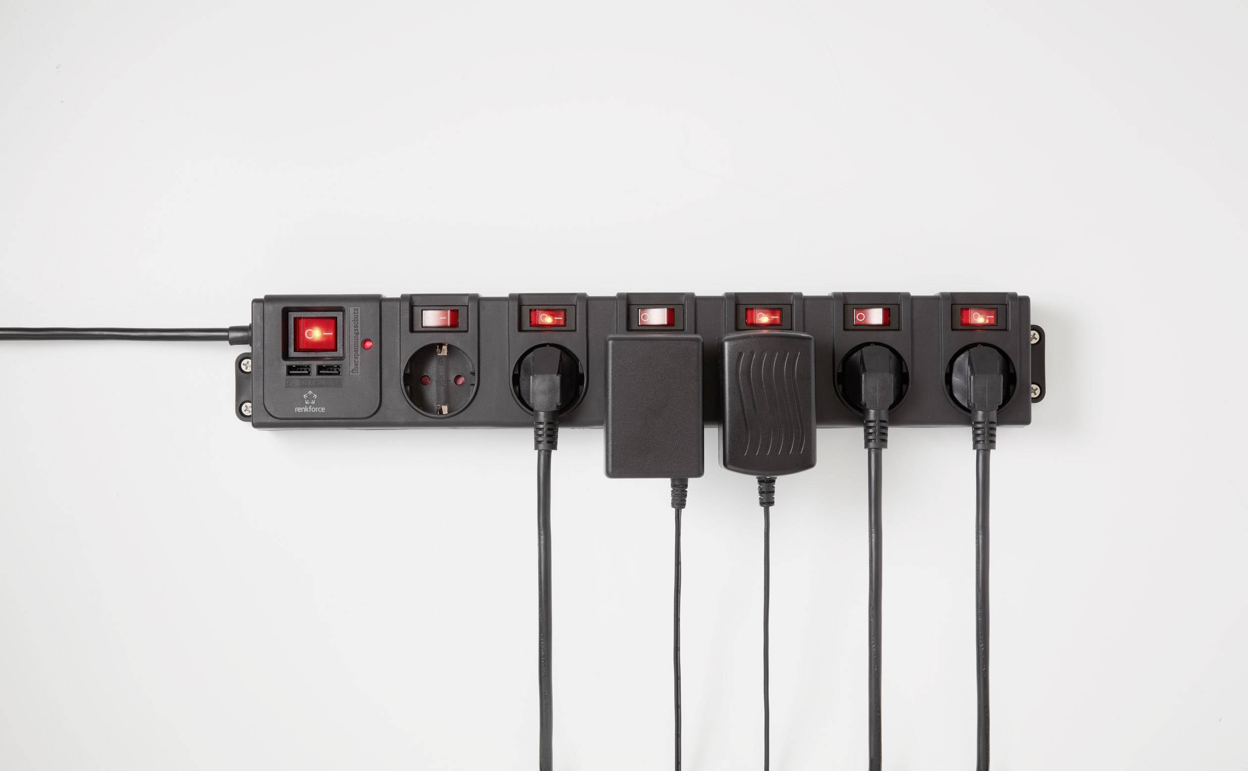 'Black power strip with six sockets, four occupied. All switches illuminated in red.'