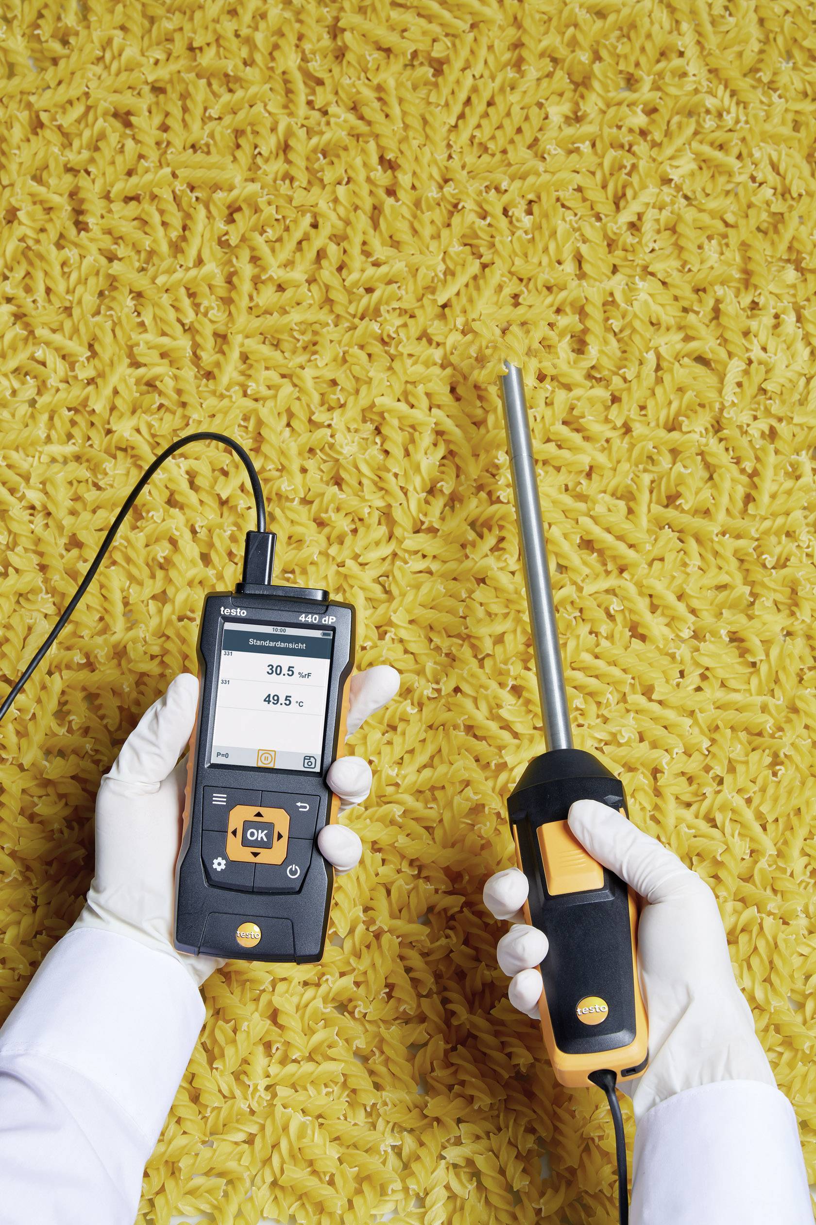 A person wearing white gloves is holding a digital measuring device over a yellow background, presumably with rice. The display shows '30.5' and '48.5'.