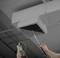 A person is holding a measuring device in front of a ventilation duct in the ceiling to check the air flow or temperature efficiency.