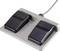 A foot pedal device with two black, ribbed pedals on a grey base, connected by a cable.