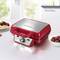 A red, modern waffle maker on a kitchen worktop, surrounded by fresh waffles and cherries. Bright kitchen in the background.