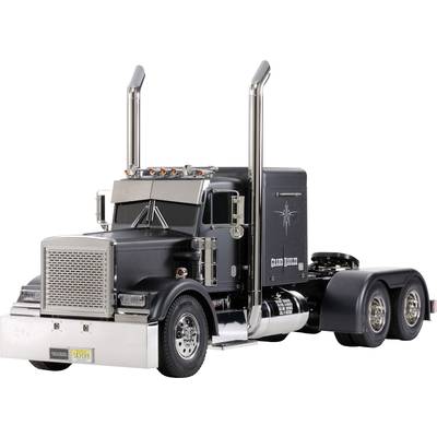 Black lorry with a long bonnet and tall exhaust pipes. The truck is parked on a flat surface.