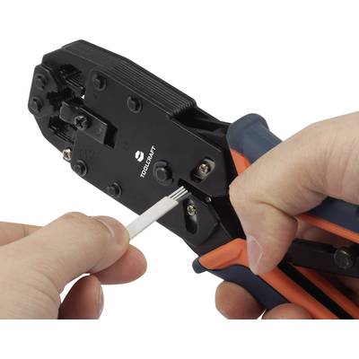 A hand is holding a crimping plier cutting a white cable tie.
