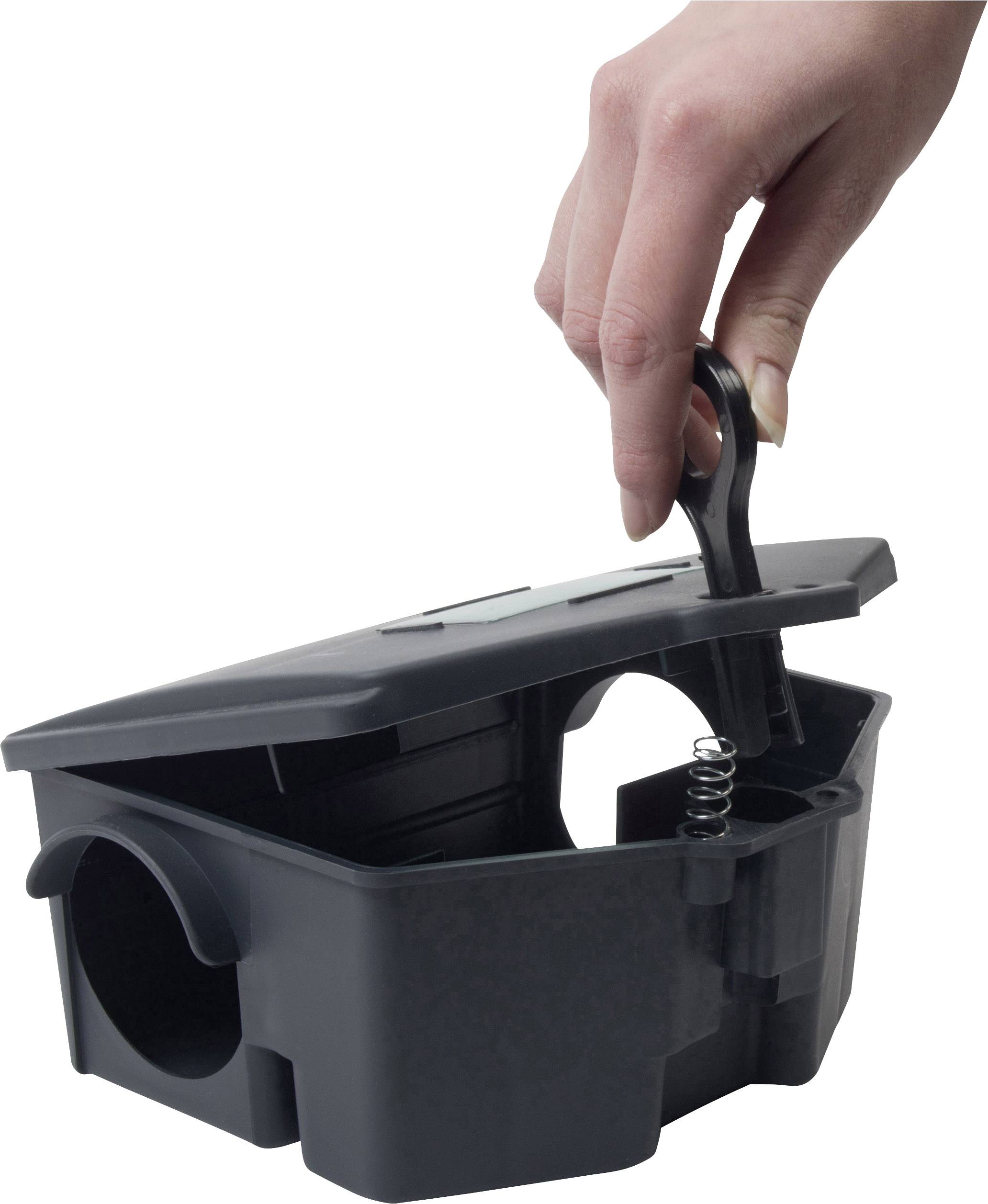 A hand is holding a black mousetrap equipped with a spring mechanism for catching mice.