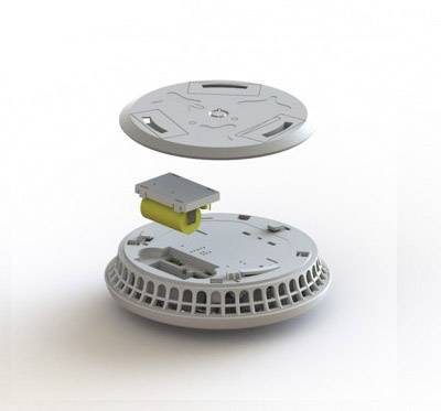 Disassembled image of a smoke detector with the cover removed, revealing the battery and showing the internal structure and components.