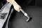 A person is cleaning the boot of a car with a vacuum cleaner.