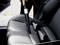 A person is vacuuming the seat of a car. The focus is on cleaning crevices and narrow areas.