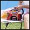 A person is using a red electric air pump on an outdoor lounger to inflate an object.