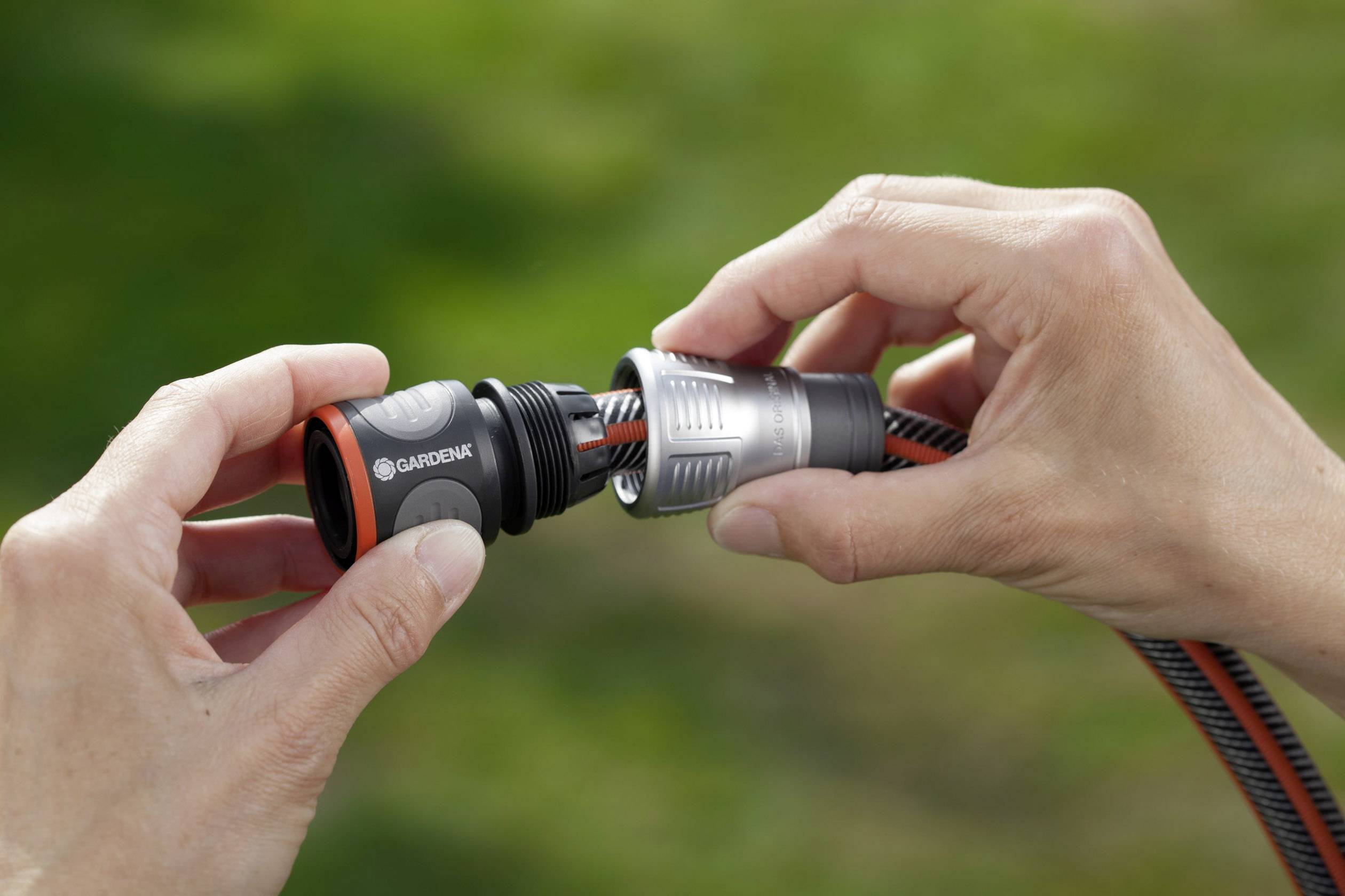 Two hands are connecting two garden hose connectors.