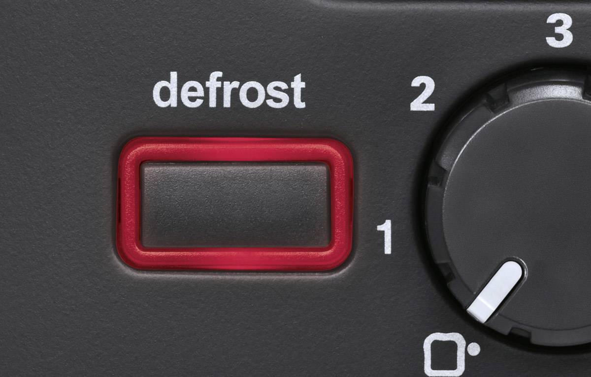 Close-up of a control panel with a red 'defrost' button and a black rotary dial that can be adjusted between 1 and 3.