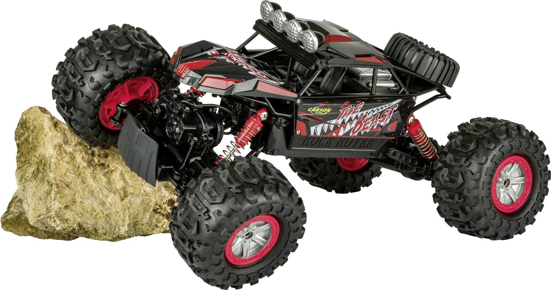 'RC monster truck with large off-road tyres climbs over a stone. Vehicle in black and red with distinctive design.'