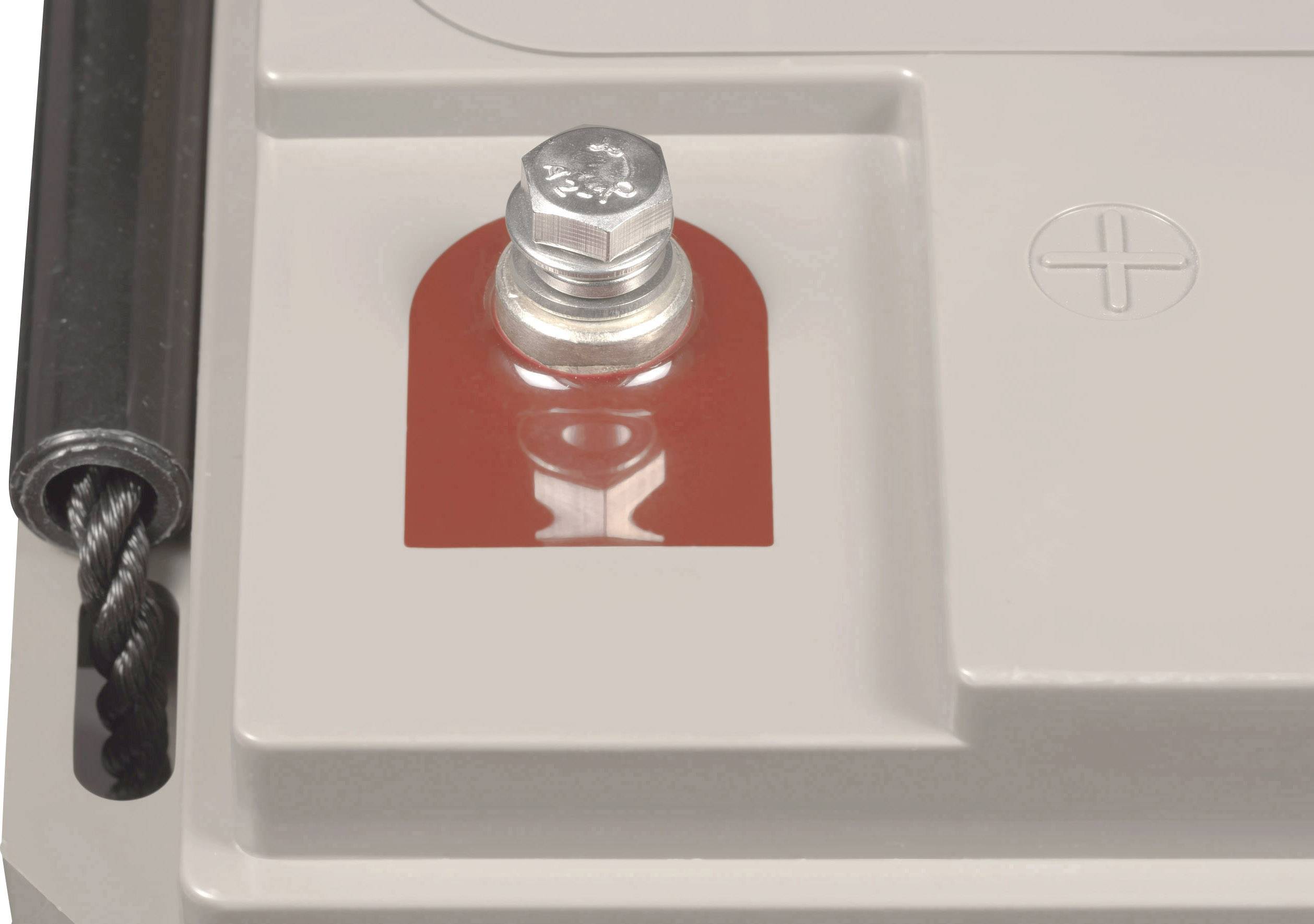 A battery contact with a red marking on the top of a grey battery. A plus sign is visible on the right.