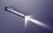 A ballpoint pen lies at an angle on a smooth, reflective surface. A beam of light illuminates its tip.