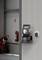 A portable charger is mounted on the wall of a warehouse, next to a fire extinguisher and a trolley with equipment.