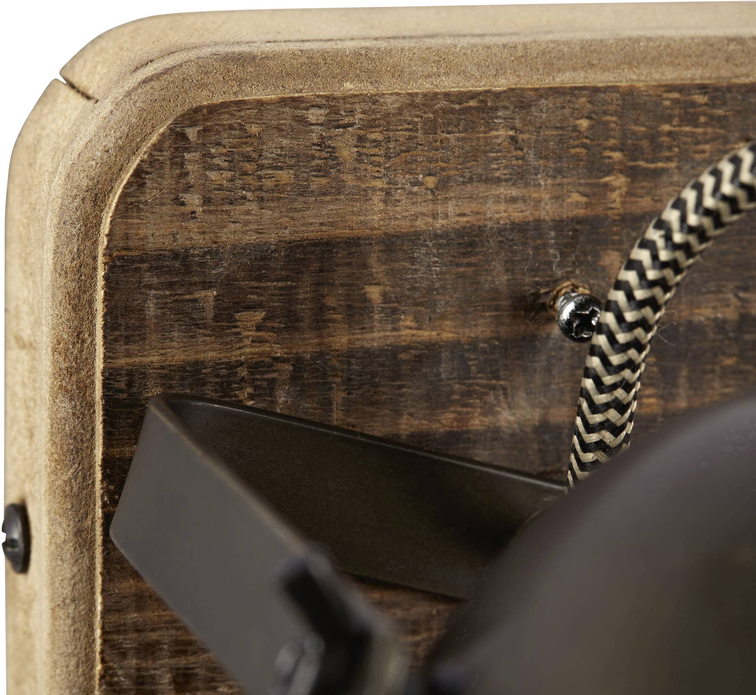 Close-up of a wooden wall board with detailed texture and an attached cable holding a lampshade.