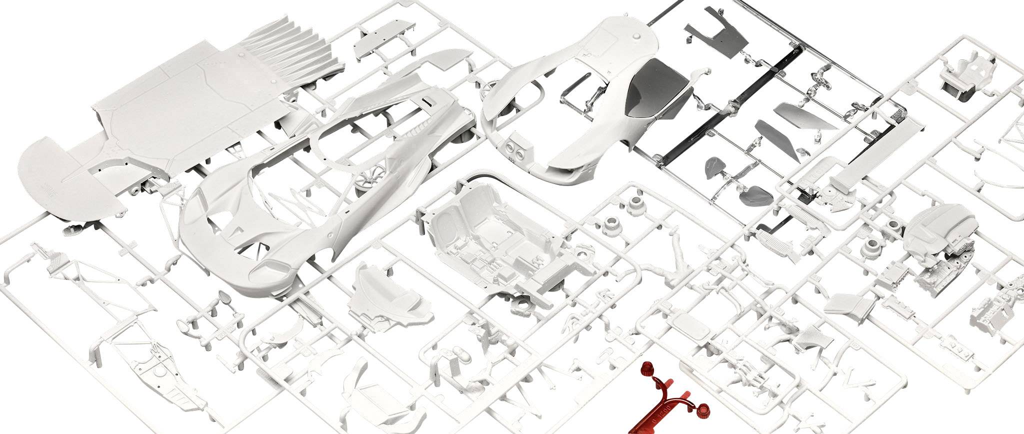 Plastic model kit with a structured grid; parts arranged side by side, including a small red element at the bottom edge.