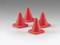 Four red traffic guidance cones stand on a grey surface, symmetrically arranged, possibly for cordoning off an area or providing a warning.