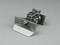Metal device with rectangular flap, ball joint, and engraving 'SC'. Potential technical or mechanical component.