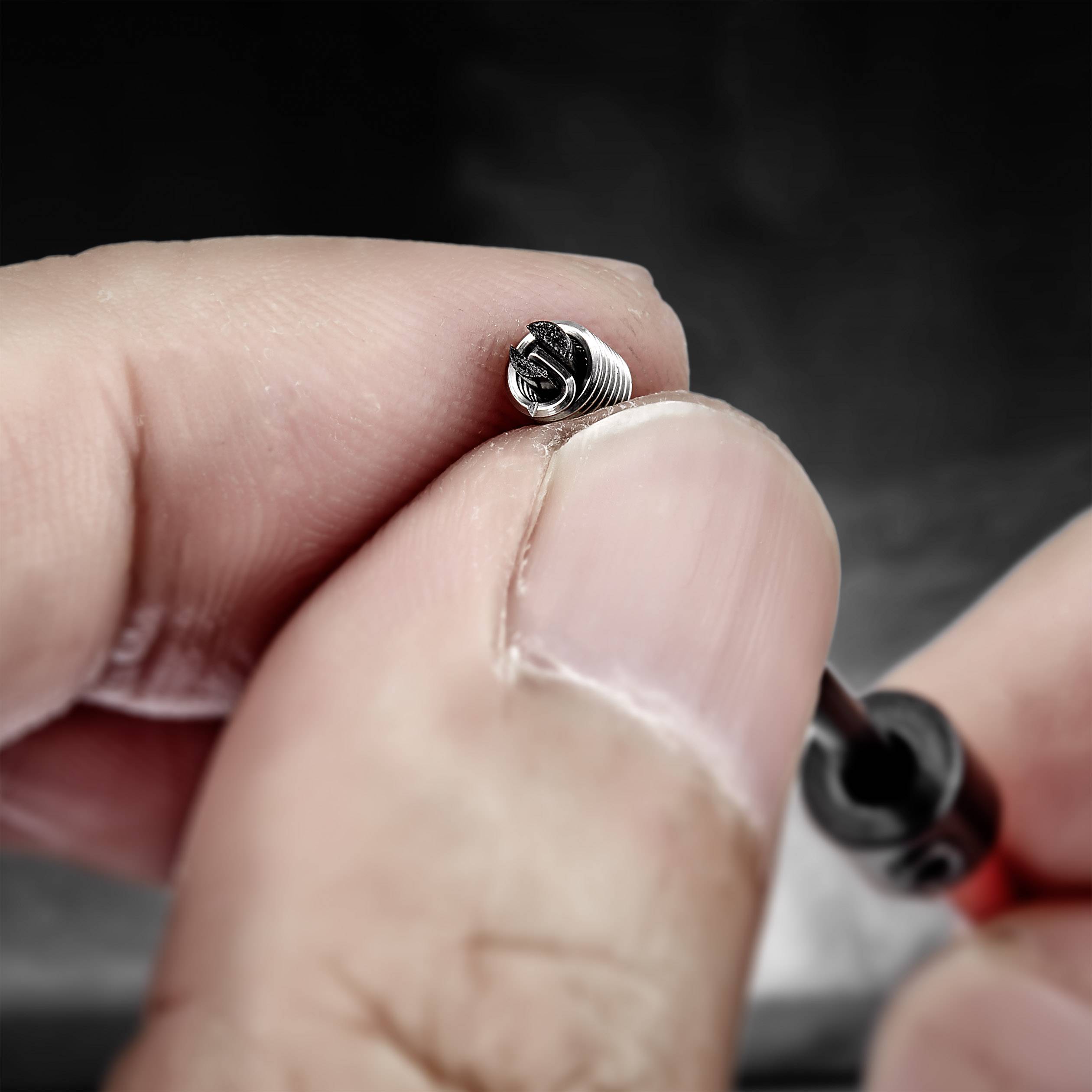 A person is holding a small screw with a screwdriver. Focus on precision and detailed work.