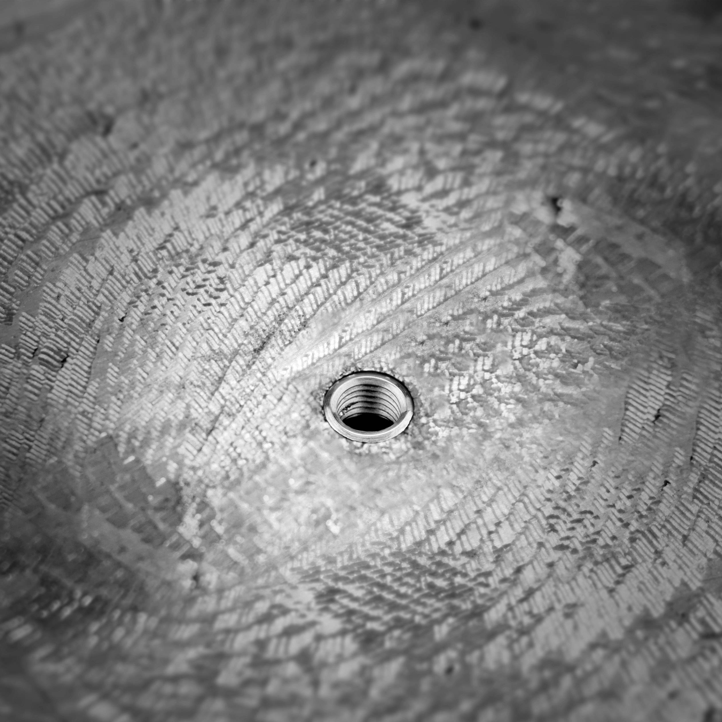 Metallic surface with a circular pattern and a central hole.