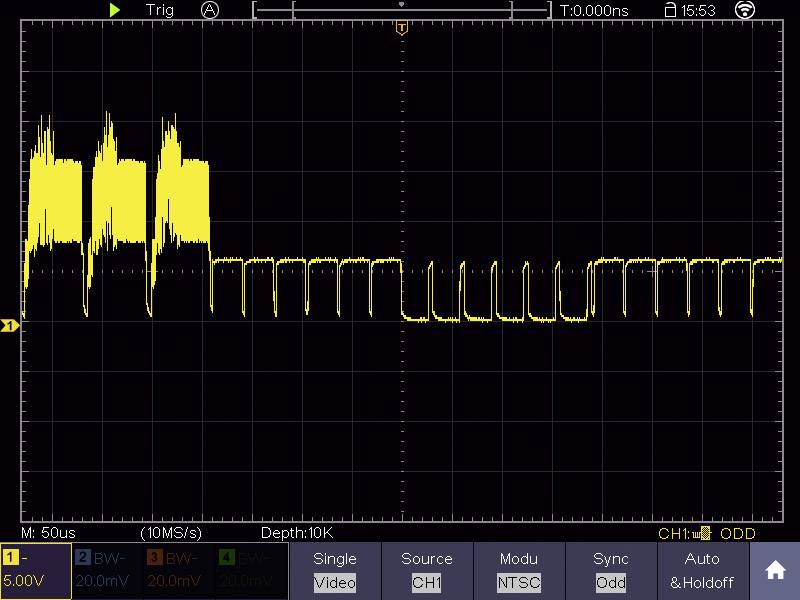 'Oscilloscope display shows a periodic digital signal with irregular spikes at the beginning, followed by regular rectangular pulses.'