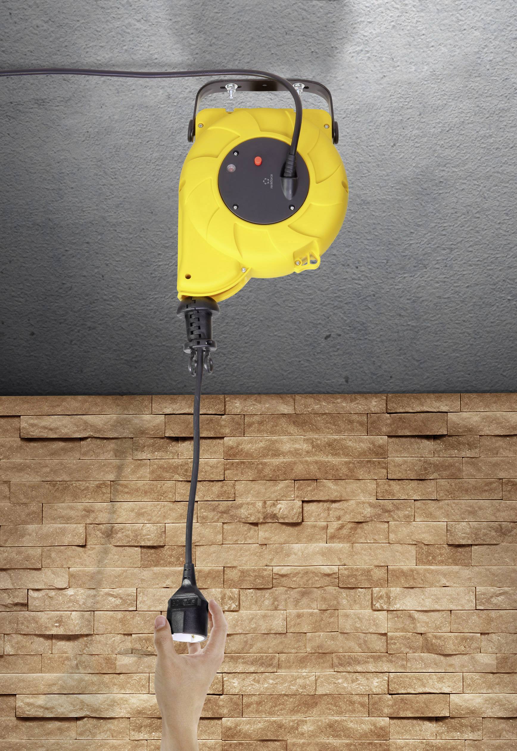 Yellow extension cable mounted on the ceiling with a hanging plug; hand reaching for the plug against a stone wall background.