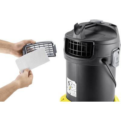 Two hands are changing a filter in a black vacuum cleaner. The filter is rectangular and is placed in front of a grid.