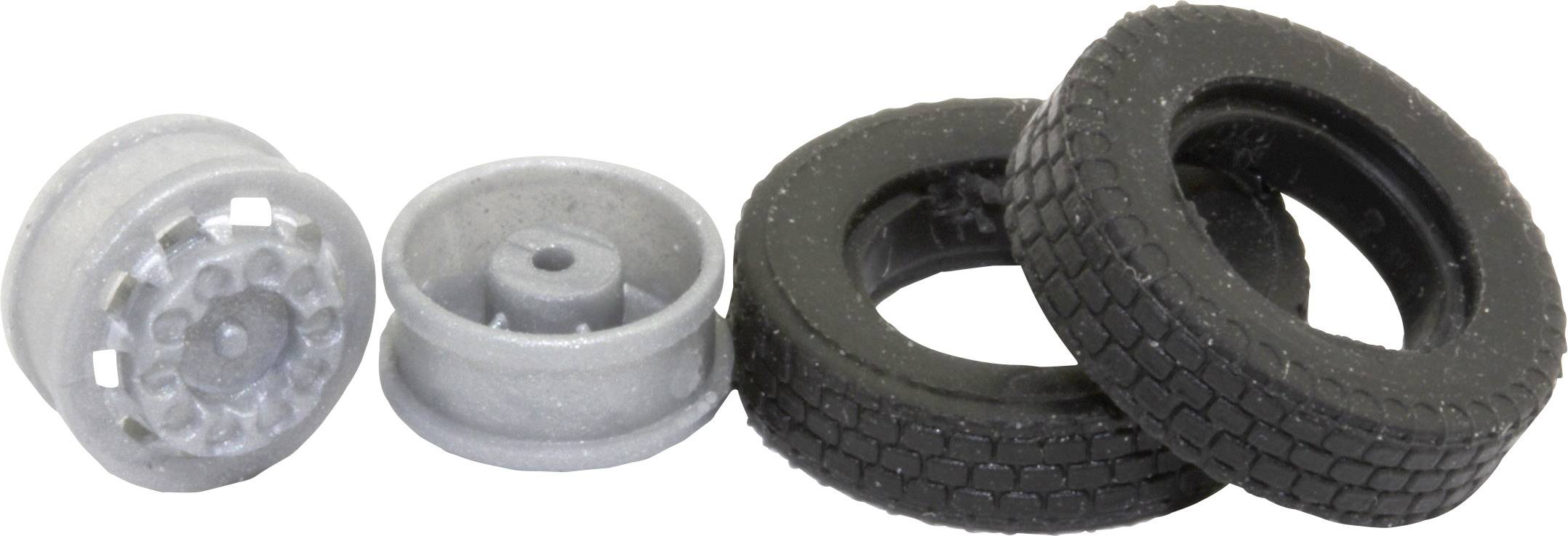 Two grey alloy wheels on the left and two black car tyres on the right are lying side by side on a white surface.
