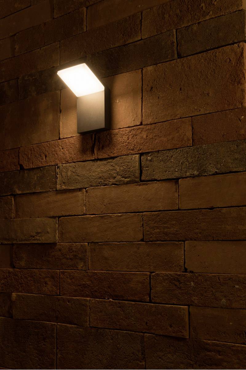 Wall light illuminates a brick wall, creating a warm and cosy atmosphere.