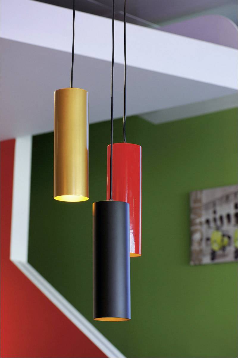 Three hanging cylindrical lamps in gold, red, and black in front of a wall in green and red.
