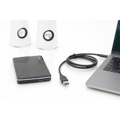 External hard drive with USB cable, next to laptop and speakers on a white table.