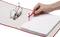 A hand is placing papers into a red lever-arch file