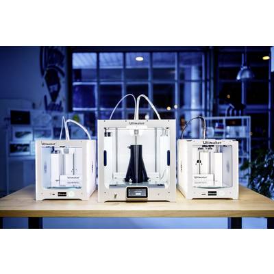 Three Ultimaker 3D printers are sitting on a table. The middle printer is larger and contains a black, cone-shaped object.