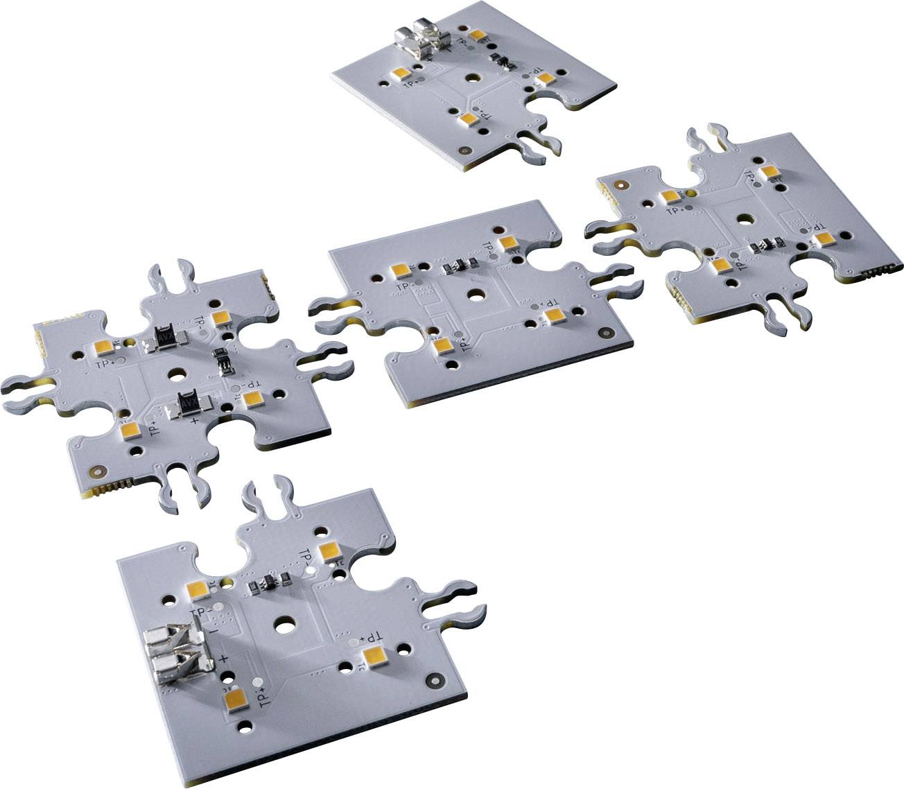 Five metallic circuit boards with electronic components arranged in a puzzle-like configuration. They display holes and various circuit pathways.