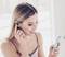 A woman is using wireless earphones and looking at her mobile phone.