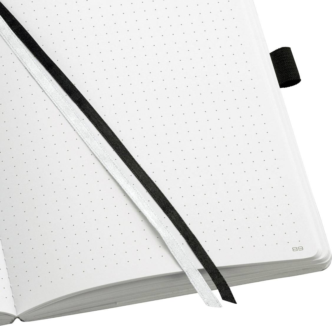 An open notebook with dotted paper and two ribbon bookmarks, one black and one white.