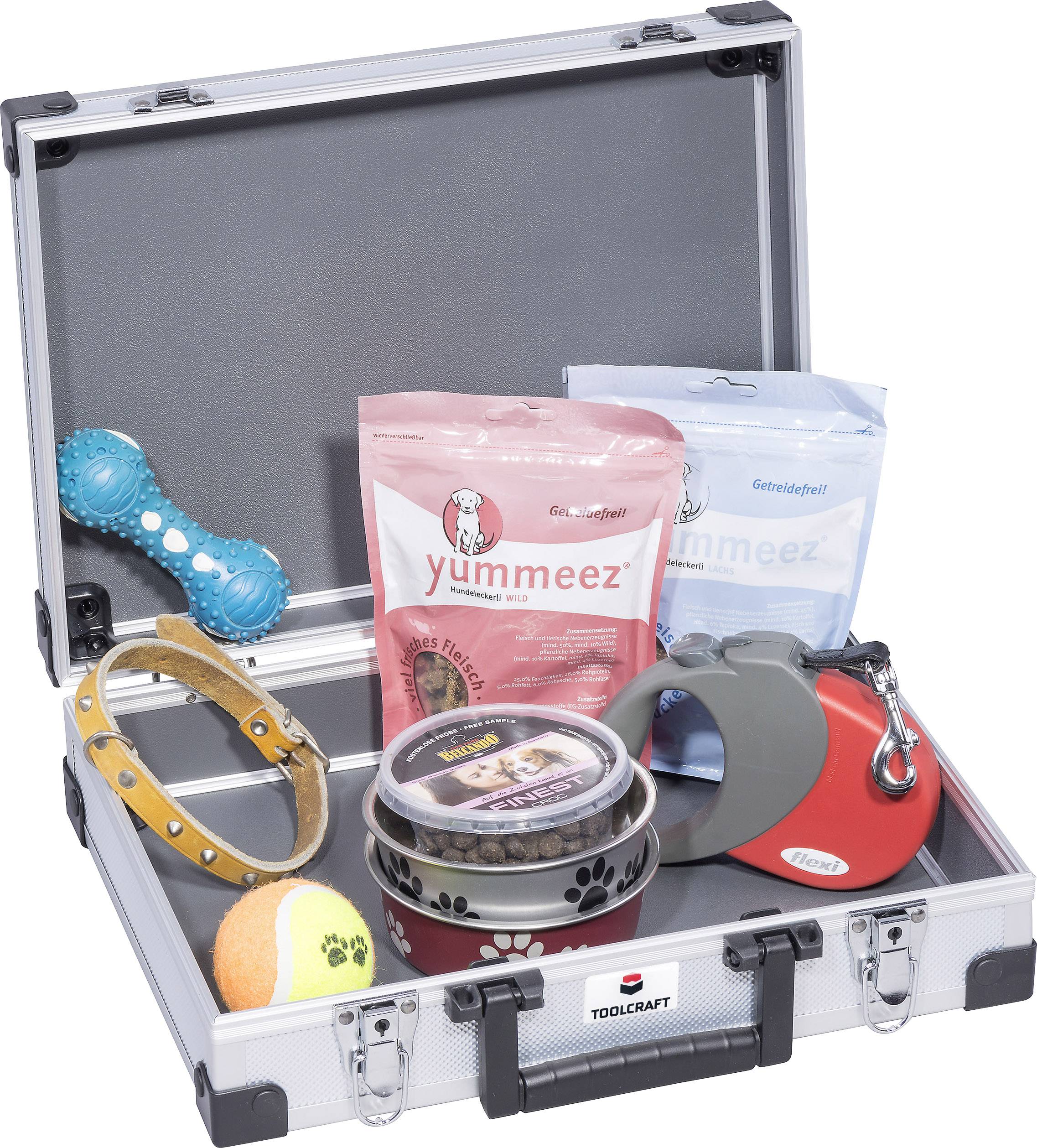 An open suitcase contains dog accessories: toys, treats, collar, bowl, extendable lead, tennis ball. Ideal for dog training.