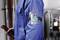 A worker in a blue uniform is wearing an ID holder with a photo on his left upper arm while working in a technical room.