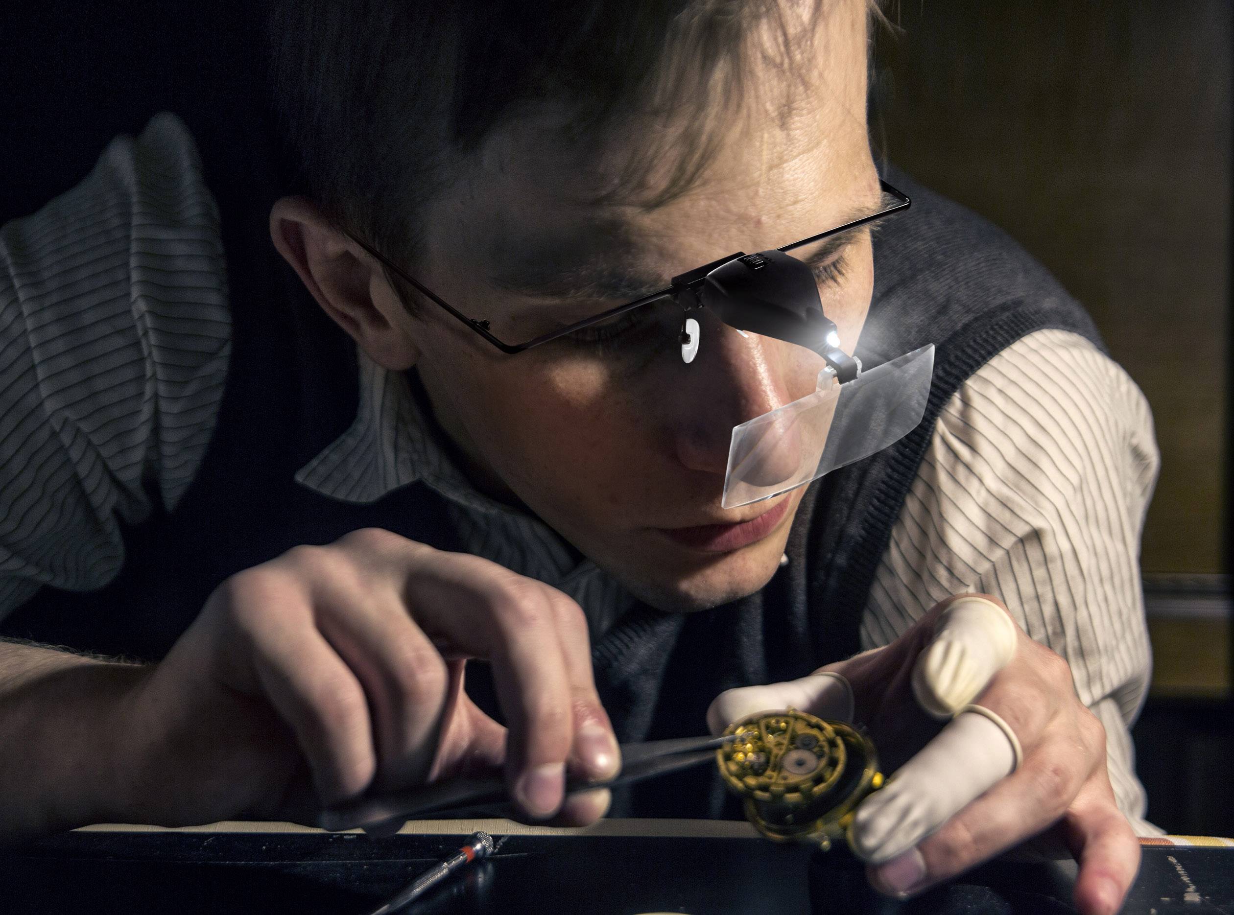 A watchmaker repairing a timepiece with a magnifying glass. The focus is on intricate craftsmanship and precision in watchmaking.