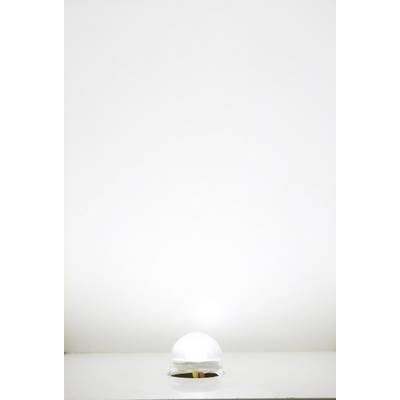 A transparent glass sphere on a white table, illuminated from above, casts a subtle shadow on the table surface.