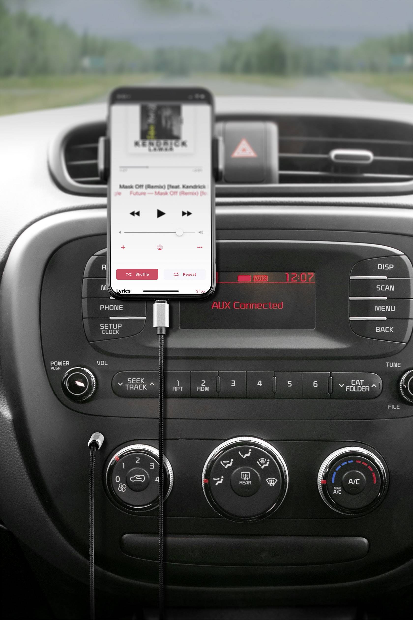 A smartphone shows a music app on the screen and is connected to the car radio. On the radio display, it reads 'AUX Connected'.